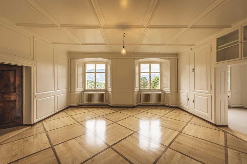 Image of a classic living space featuring white marble floors, paneled walls and ceiling, and pendant lighting.