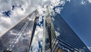 Image of mirrored skyscrapers reflecting clouds in the sky.
